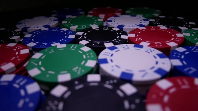 Poker Table With Poker Chips Turns In Casino. Many Poker Chips Spins on the Table in Darkness