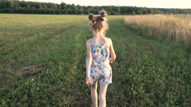 A little girl runs across the field like an airplane. Towards sunset. Concept - energy of youth, happy childhood, dreams. Steadicam shot