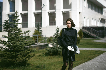 street portrait of a student girl dressed fashionably in dark clothes, on an autumn sunny day