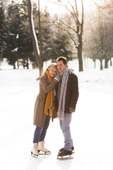 Fototapeta premium Senior couple in sunny winter nature ice skating, hugging.