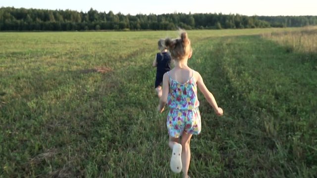 A little girl and boy runs across the field like an airplane. Towards sunset. Concept - energy of youth, happy childhood, dreams. Steadicam shot
