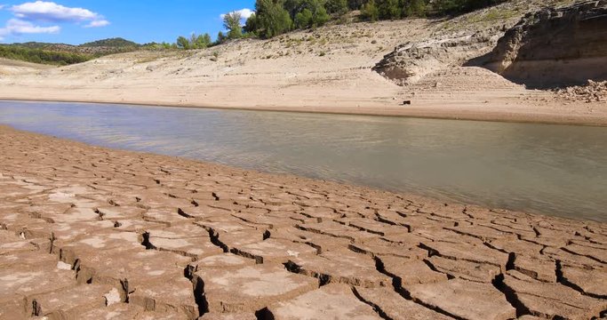 4k video. Panning shot from river with water streaming to dry earth ground, in Entrepenas reservoir, in Guadalajara, Castilla, Spain Europe
