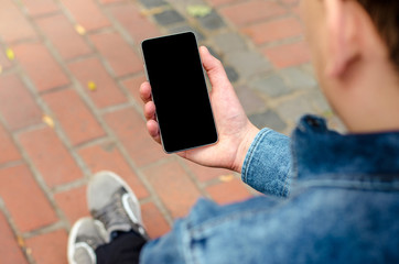 close up smartphone in hands a young hipster business man in denim shirt and jeans on the...