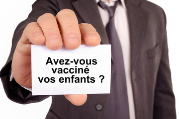 Homme tenant une carte sur laquelle est &eacute;crit avez-vous vaccin&eacute; vos enfants 