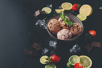 Portion of ice cream scoops with fruit on black
