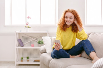 Smiling girl at home chatting online on smartphone