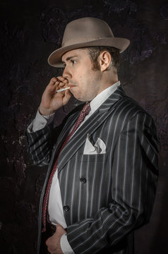 Private detective in hat with cigarette. Gangster studio shot