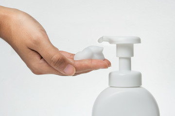 Fototapeta na wymiar Close up Woman hand take cleaner foam from Pure white plastic pump bottle
