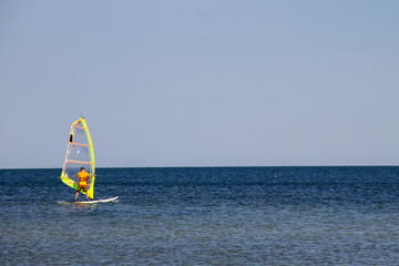 Windsurfing. Surfer exercising in calm sea or ocean.
