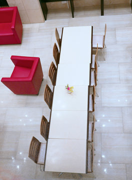 Langer Tisch mit Stühlen und einzelne rote Sessel, von oben gesehen
