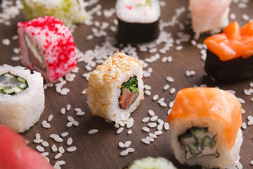 Set of sushi, maki and rolls with sesame on wooden rustic background, closeup