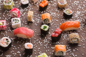 Set of sushi, maki and rolls with sesame on wooden rustic background