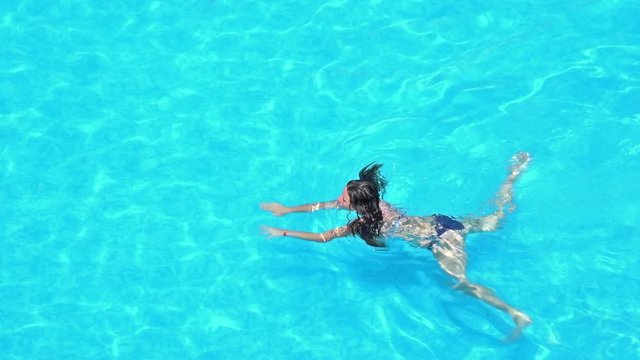 Girl swimming in pool,  aerial trekking shot