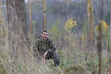 Man in camouflage and with guns in a forest belt on a spring hunt