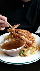 Mann isst Gebackene Ente auf gebratenen Reisnudeln an Hoisin Soße mit Stäbchen