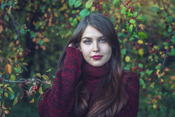 Portrait of woman in red dress in dark autumn cherry grove. Concept for fashion art design as a background for text