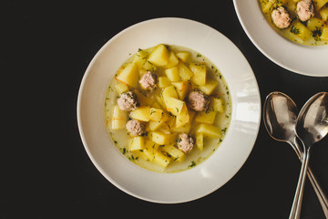 soup with meatballs in a white plate on a black background