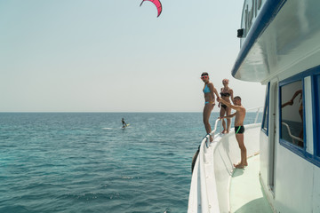 Girls jump into the water from the yacht