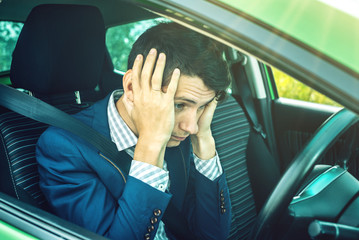 Man driver sitting in the car clutching his head. Concept of accidents on the road and dangerous...