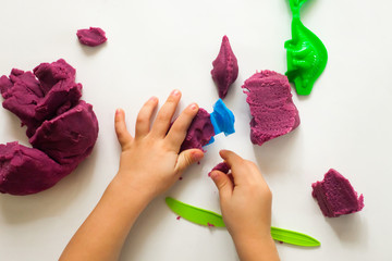 Child's hands with colorful clay. Toddler playing and creating toys from play dough. Boy molding modeling clay. Art therapy for anxious children, cure for stress free