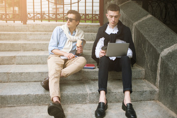 Fototapeta premium Social communication. Fashion youth outdoors. Two stylish male hipsters on coffee break, creative leisure time, technology concept