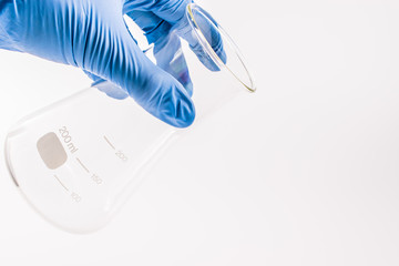 hand of scientist hold empty chemical laboratory beaker. Research science and medical laboratory.