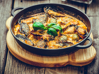mussels with cheese sauce, in a frying pan, wooden background