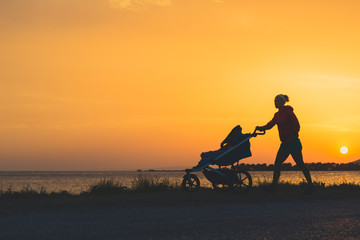 Mother walking on a beach with stroller enjoying motherhood