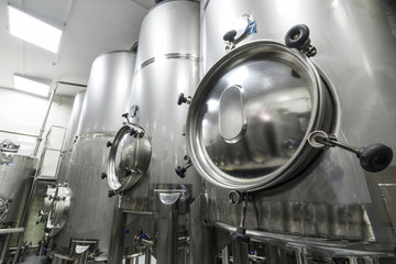 Fototapeta na wymiar A lot of stainless steel tanks with large round hatches, modern beverage production.