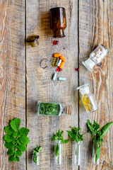 Herbal medicine. Leaves, bottles, pills on wooden background top view