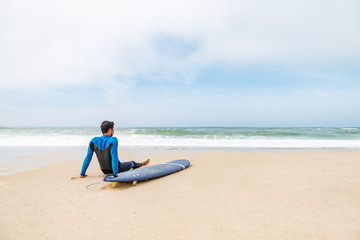 Obraz premium Young male surfer wearing wetsuit