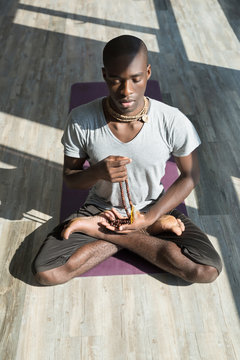 Athletic young man meditating and doing yoga in studio