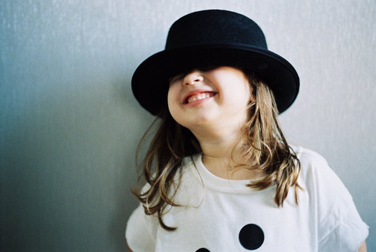 Beautiful young girl in an over sized t shirt playing with a hat