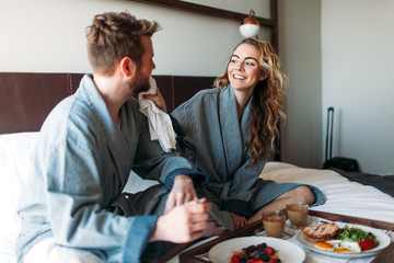 Young couple enjoying room service in bed