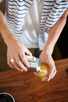 Bartender pouring steamed milk in latte