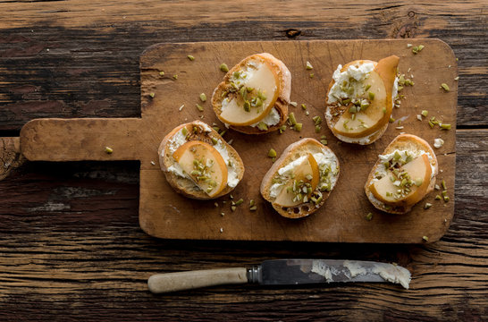 Crostini with Goats Cheese and  Pear on Wood Cutting Board