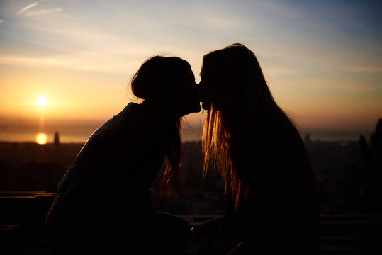 Silhouette Of Two Young Women Kissing On The Beach