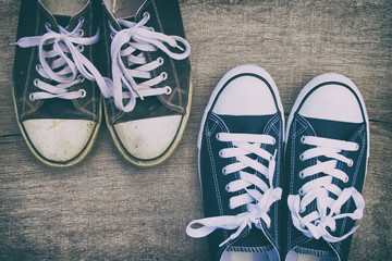 Old sneakers vs new sneakers, canvas shoes on a wooden board. Top view. 