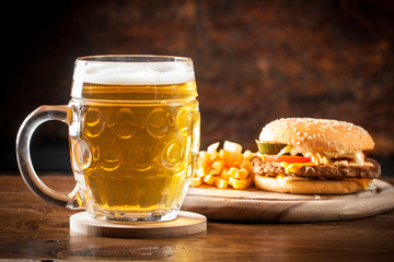 A glass of fresh cold light beer with gourmet hamburgers and wheat in a bar and a dark pub