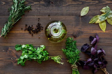 Bottle with organic oil with herbs ingredients on wooden background top view