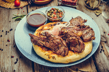 two pieces of of grilled pork with herbs on a paper on an old table top view horizontal close-up