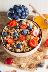 Healthy breakfast concept with oat flakes and fresh berries on rustic background. Food made of granola, muesli. Healthy banana smoothie with blackberries, muslie, strawberries, blueberries and honey.