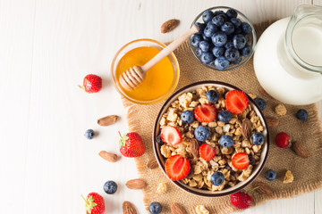 Healthy breakfast concept with oat flakes and fresh berries on rustic background. Food made of granola, muesli. Healthy banana smoothie with blackberries, muslie, strawberries, blueberries and honey.