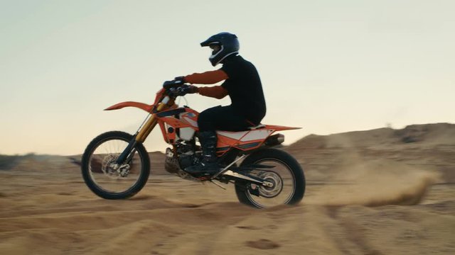 Professional Motocross Biker Drives His FMX Motorcycle of the Dune on the Off-Road Track. Shot on RED EPIC-W 8K Helium Cinema Camera.
