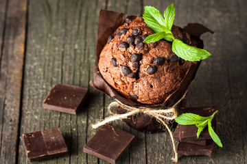 chocolate dark muffin with a leaf of mint on a wooden table with cinnamon, anise, chocolate
