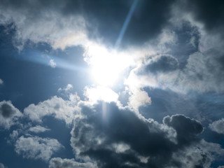 Fototapeta na wymiar Blue sky with fluffy clouds and sun peeping through