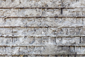 Fragment of a gray concrete wall with metal structures