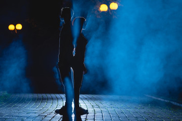 The man and woman stand on the smoky street. night time