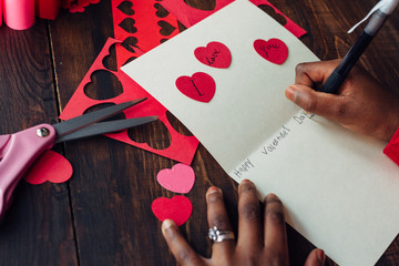 African American girl's hand writing a valentine card
