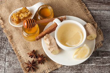 A glass cup of green natural tea with ginger, lemon, mint and honey on wooden rustic background. Healthy drink.